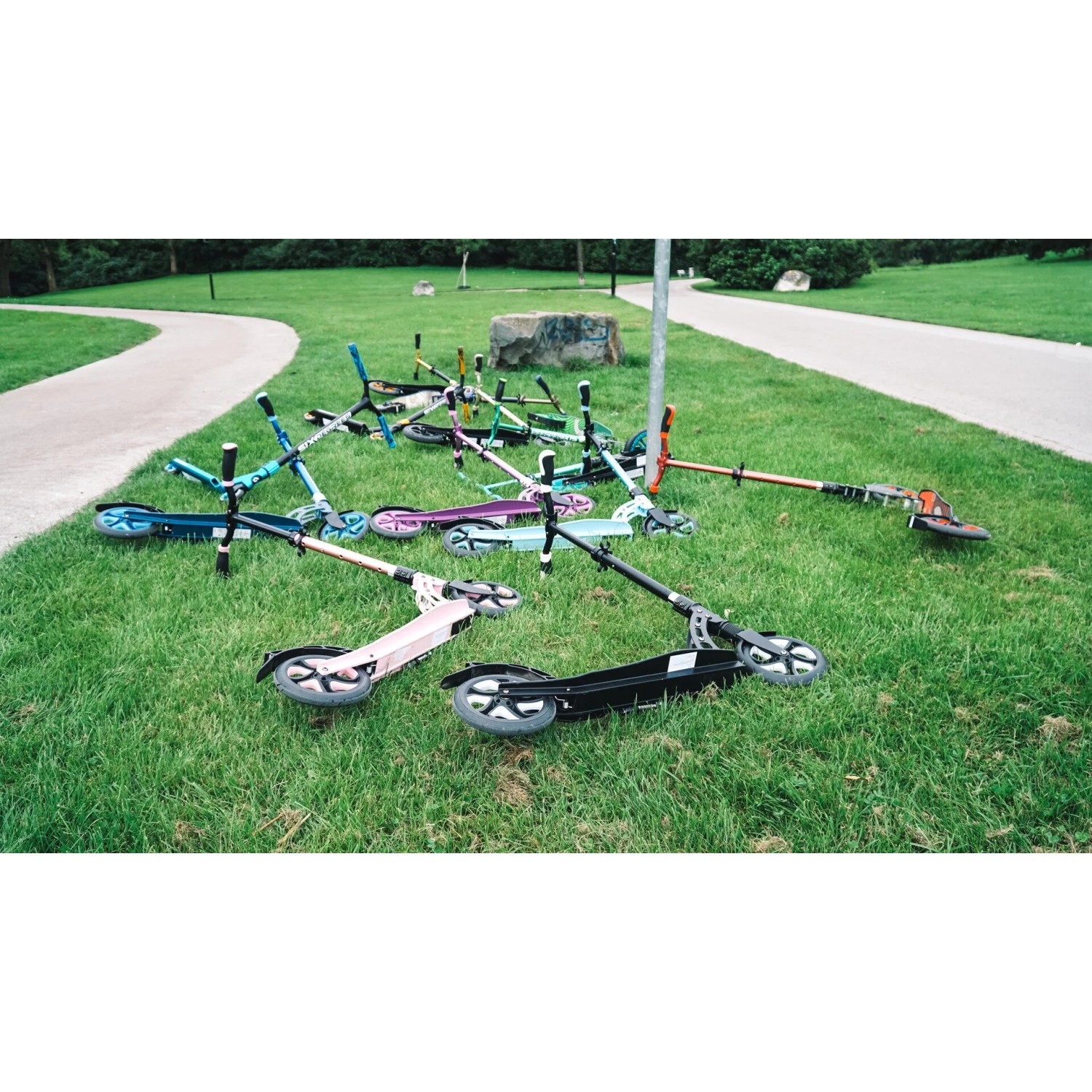 Mehrere Six Degrees Aluminium Scooter in verschiedenen Farben auf einer Wiese.