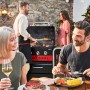 Char-Broil Gas2Coal 330 Kombigrill mit Gästen beim Grillen im Garten.