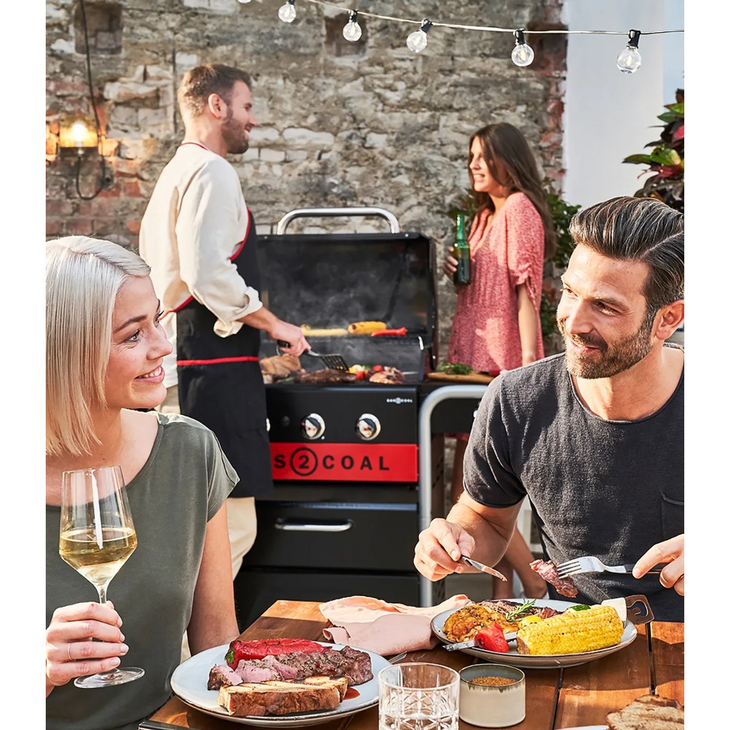 Char-Broil Gas2Coal 330 Kombigrill mit Gästen beim Grillen im Garten.