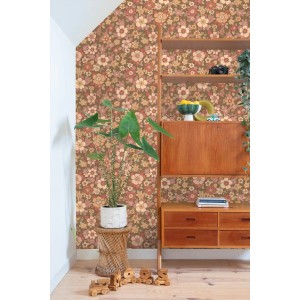 ESTAhome Vliestapete mit Retro Blumenmuster in Rot, Braun und Beige an einer Wand, kombiniert mit Holzmöbeln.