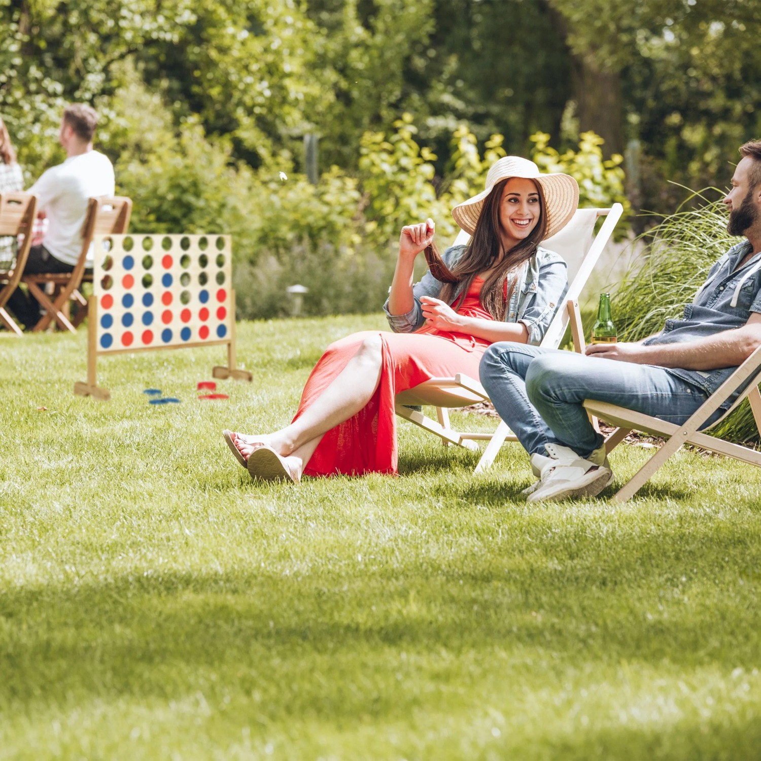 XXL Vier Gewinnt Spiel aus Holz im Garten mit entspannten Personen.