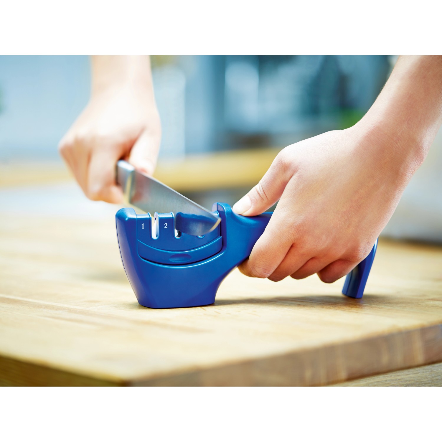 LUX Messerschärfer in Aktion: Messer wird durch blauen Messerschärfer gezogen.