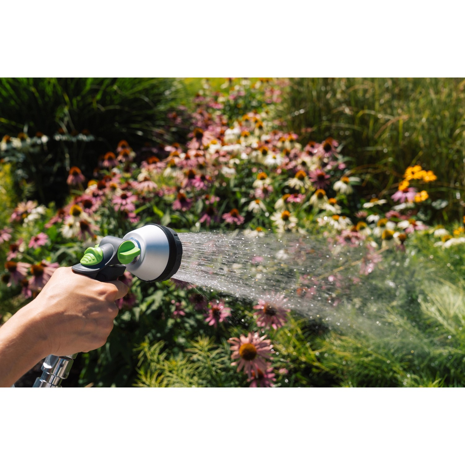 Geka Multibrause Plus 3S Grau in Aktion: Hand hält Gartenspritze, bewässert Blumen.