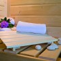 Innenansicht der Woodfeeling Sauna Tromsö mit Handtuch, Blumen und Saunasteinen auf der Saunabank.