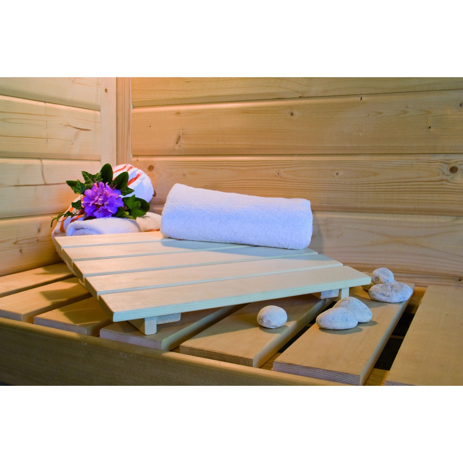 Innenansicht der Woodfeeling Sauna Tromsö mit Handtuch, Blumen und Saunasteinen auf der Saunabank.