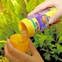 JBL Pronovo Color Flakes Fischfutter wird in einen gelben Dosierbecher gefüllt.
