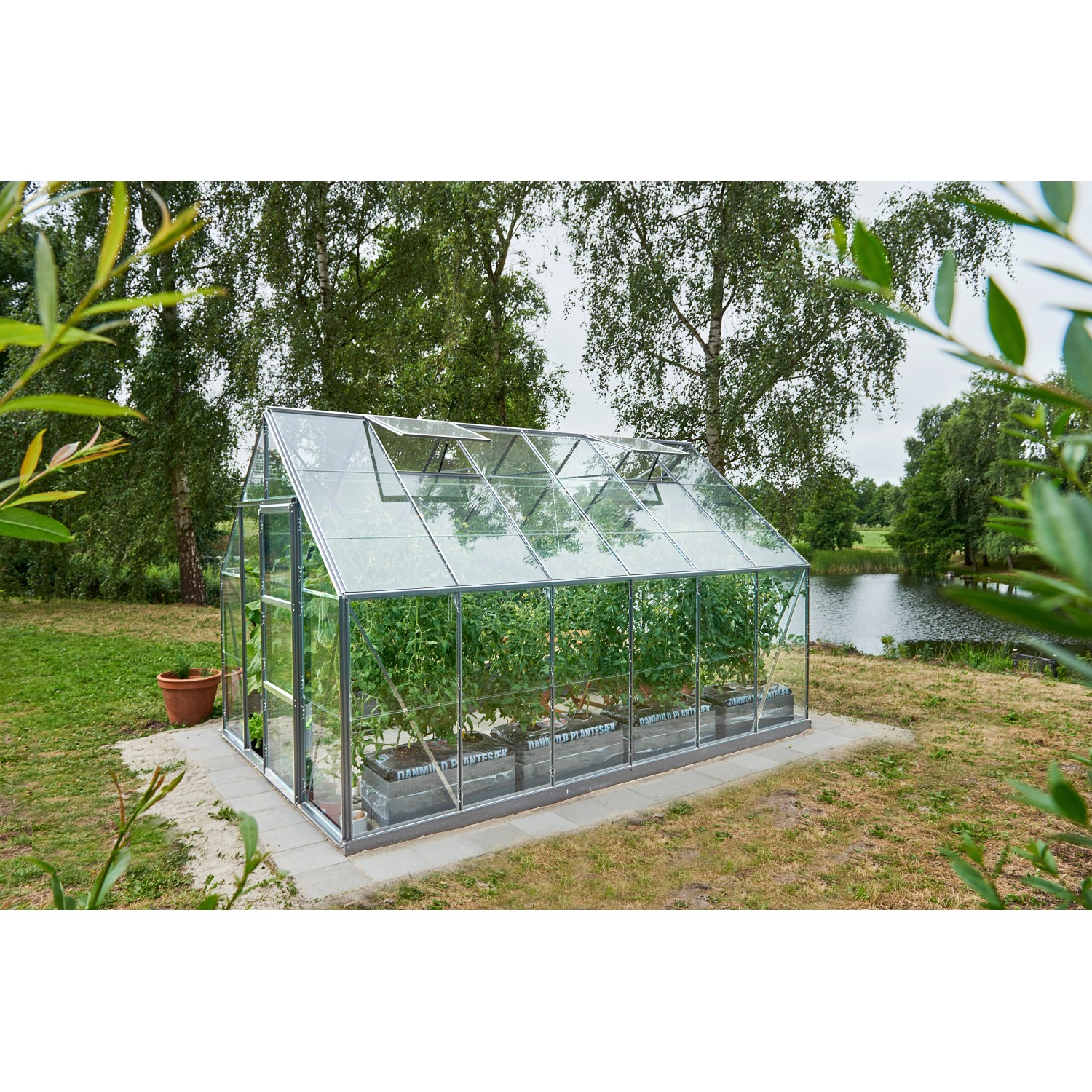 Halls Gewächshaus Universal 128 aus Alu mit 9,9 m² und Fundamentrahmen im Garten.