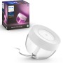 Philips Hue Iris Tischleuchte, weiße Lampe mit Farbwechselfunktion, neben Produktverpackung.