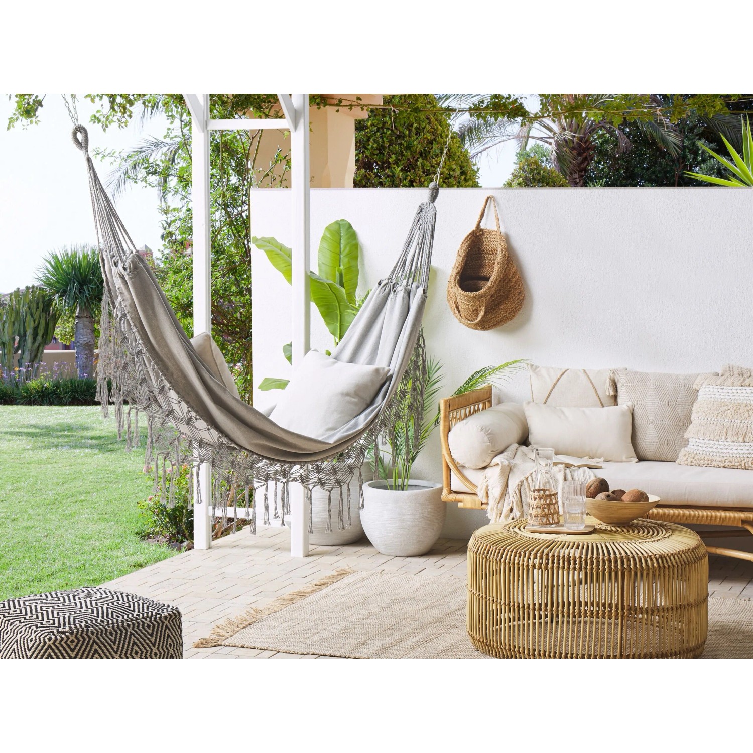 Graue Beliani Hängematte (150x290x1) mit Kissen auf Terrasse. Ideal zum Entspannen im Garten.