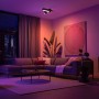 Schwarze Philips Hue Centris Cross LED-Deckenleuchte mit drei Spots in Wohnzimmer-Szene.