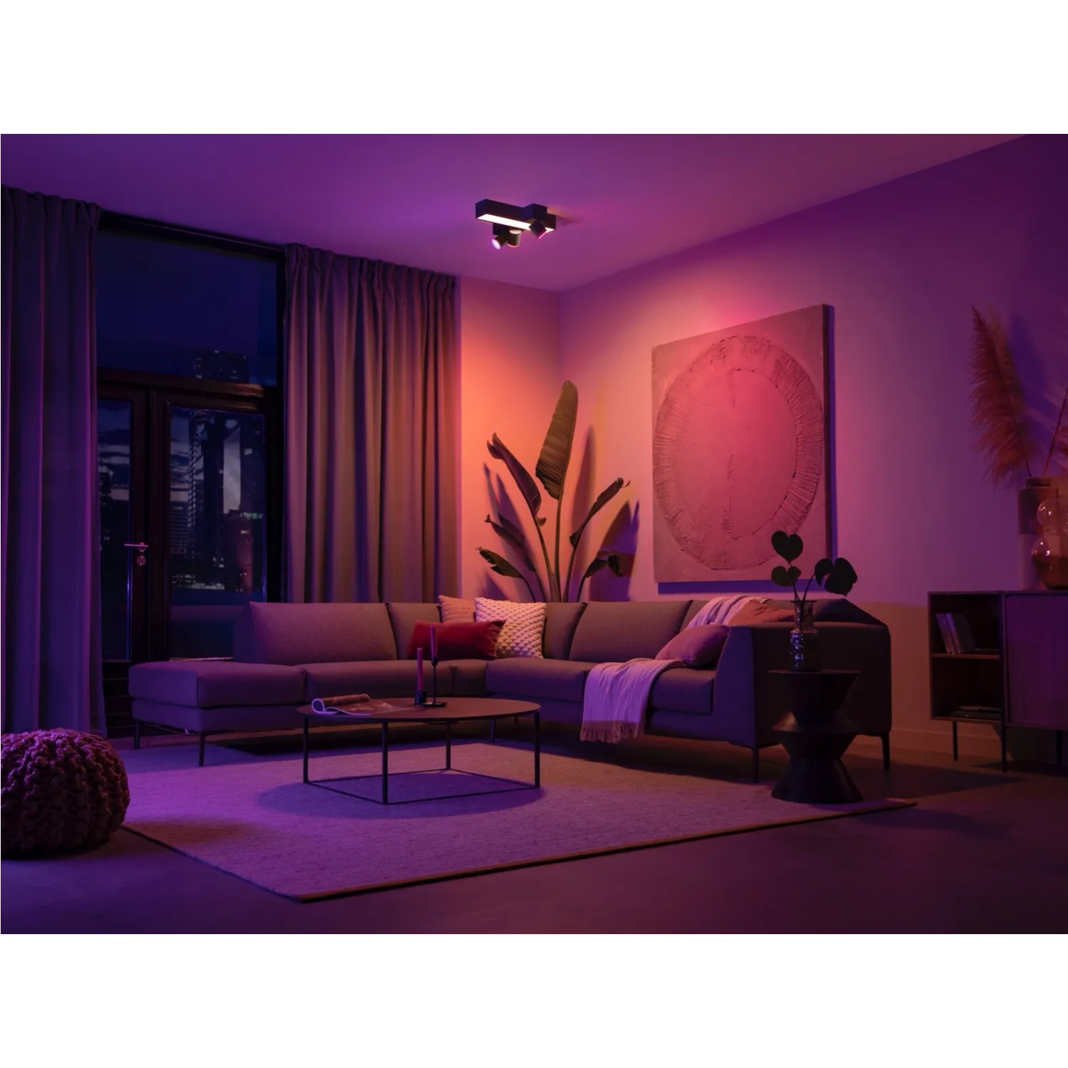 Schwarze Philips Hue Centris Cross LED-Deckenleuchte mit drei Spots in Wohnzimmer-Szene.