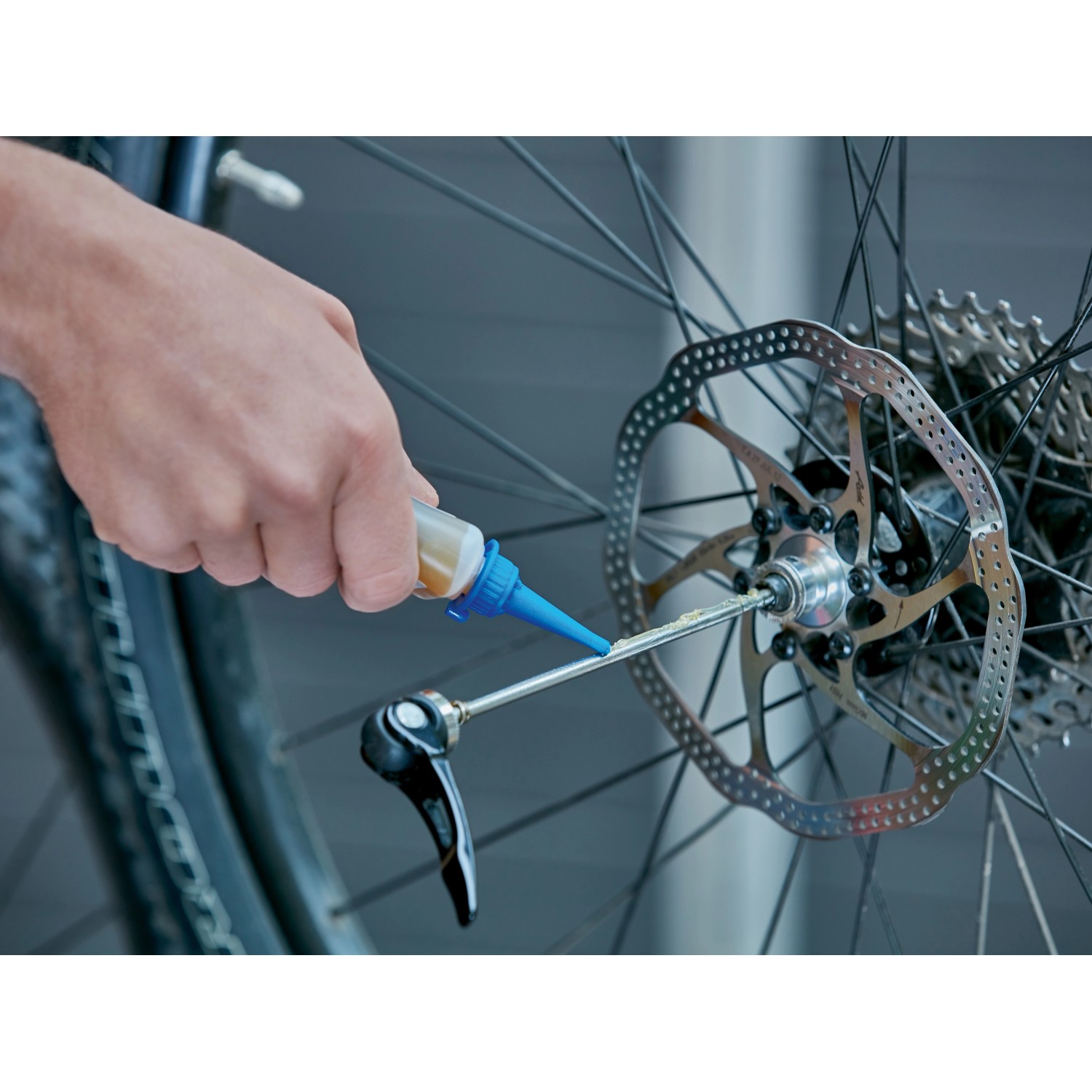 Anwendung von Mehrzweckfett auf ein Fahrradbremssystem. Schmierstoff für Fahrräder.