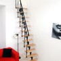 Minka Raumspartreppe Nizza Buche/Schwarz, gerade Treppe mit Buchenholzstufen und schwarzem Geländer im Wohnraum.