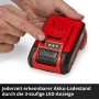 Hand drückt Taste auf rotem Einhell Power X-Change 4 Ah Akku. 3 grüne LEDs zeigen Ladezustand an.