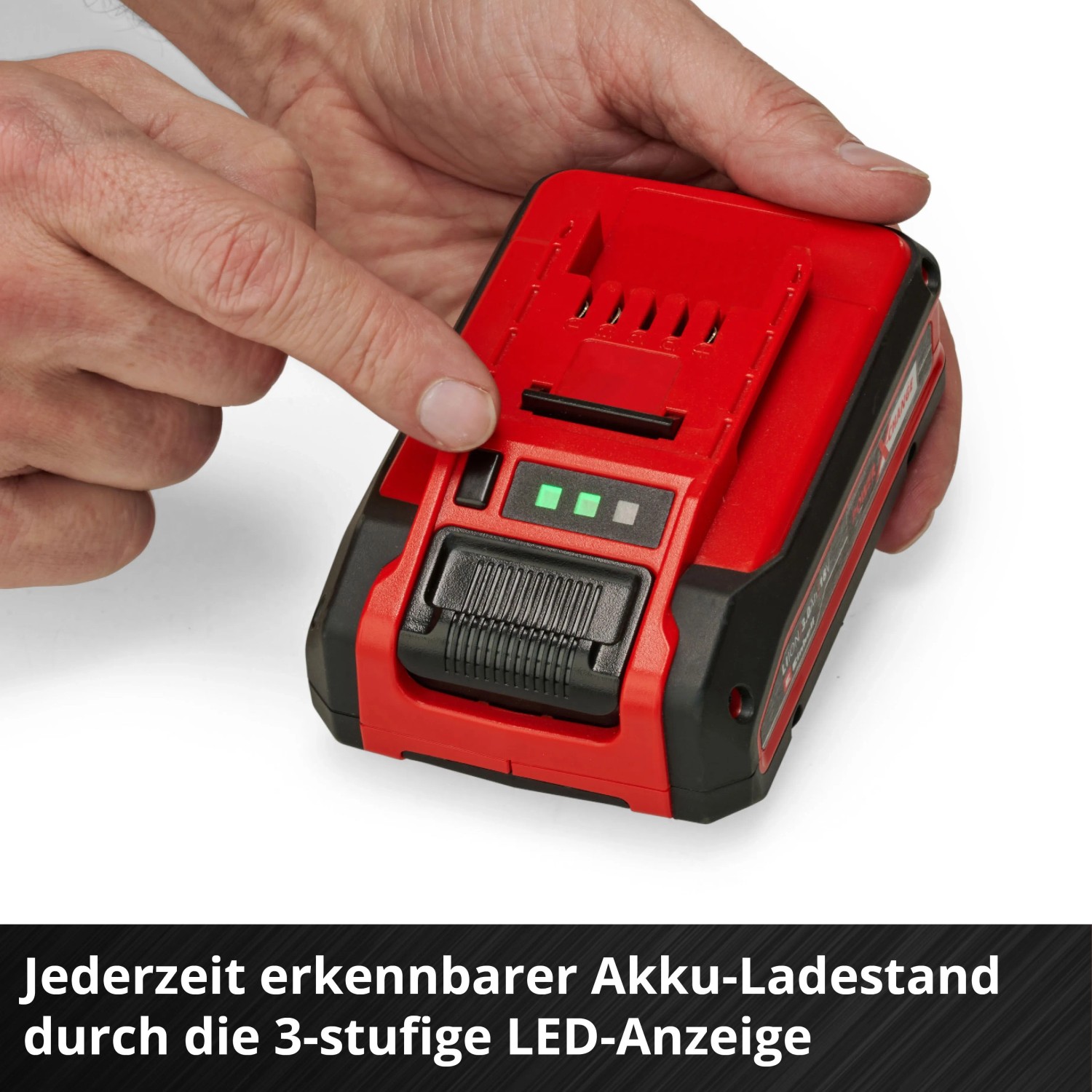Hand drückt Taste auf rotem Einhell Power X-Change 4 Ah Akku. 3 grüne LEDs zeigen Ladezustand an.