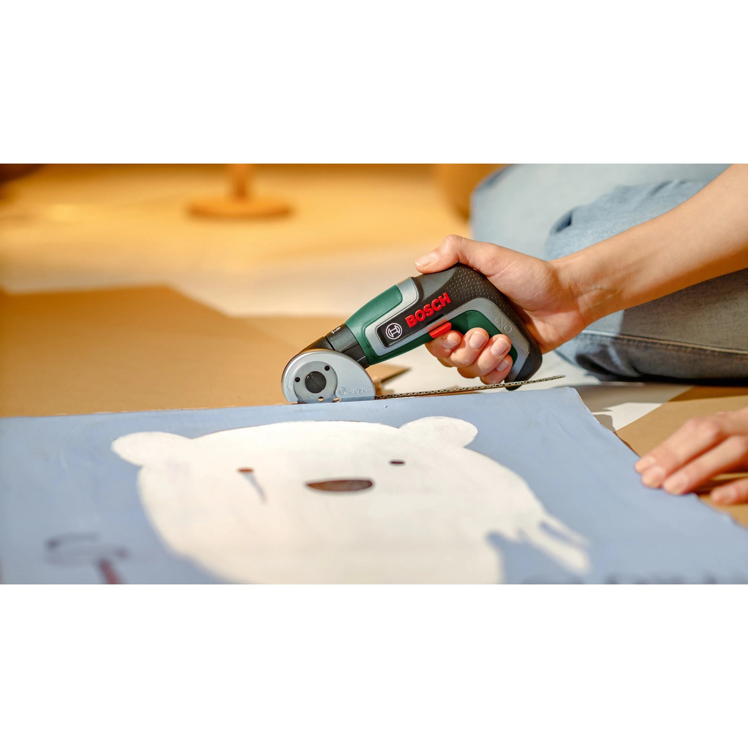 Bosch IXO 7 Akkuschrauber mit Schneideaufsatz im Einsatz, schneidet Stoff.