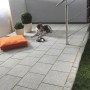Verlegte, graue Terrassenplatten aus Naturstein (Sino Grau, 60x30 cm) auf einer Terrasse mit Hund.
