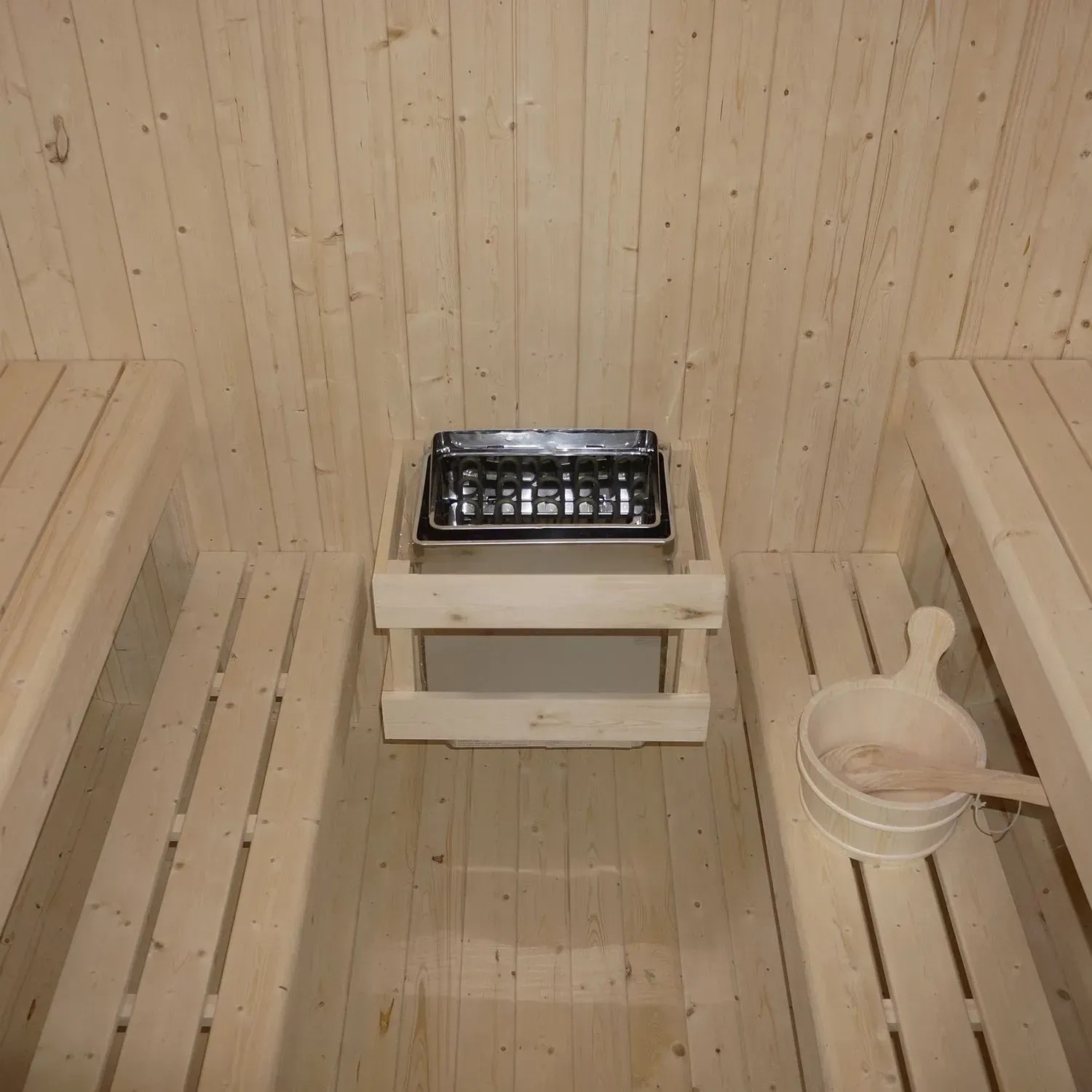 Innenansicht Artsauna Cube Fasssauna Fjora mit Saunaofen, Holzbänken und Zubehör.