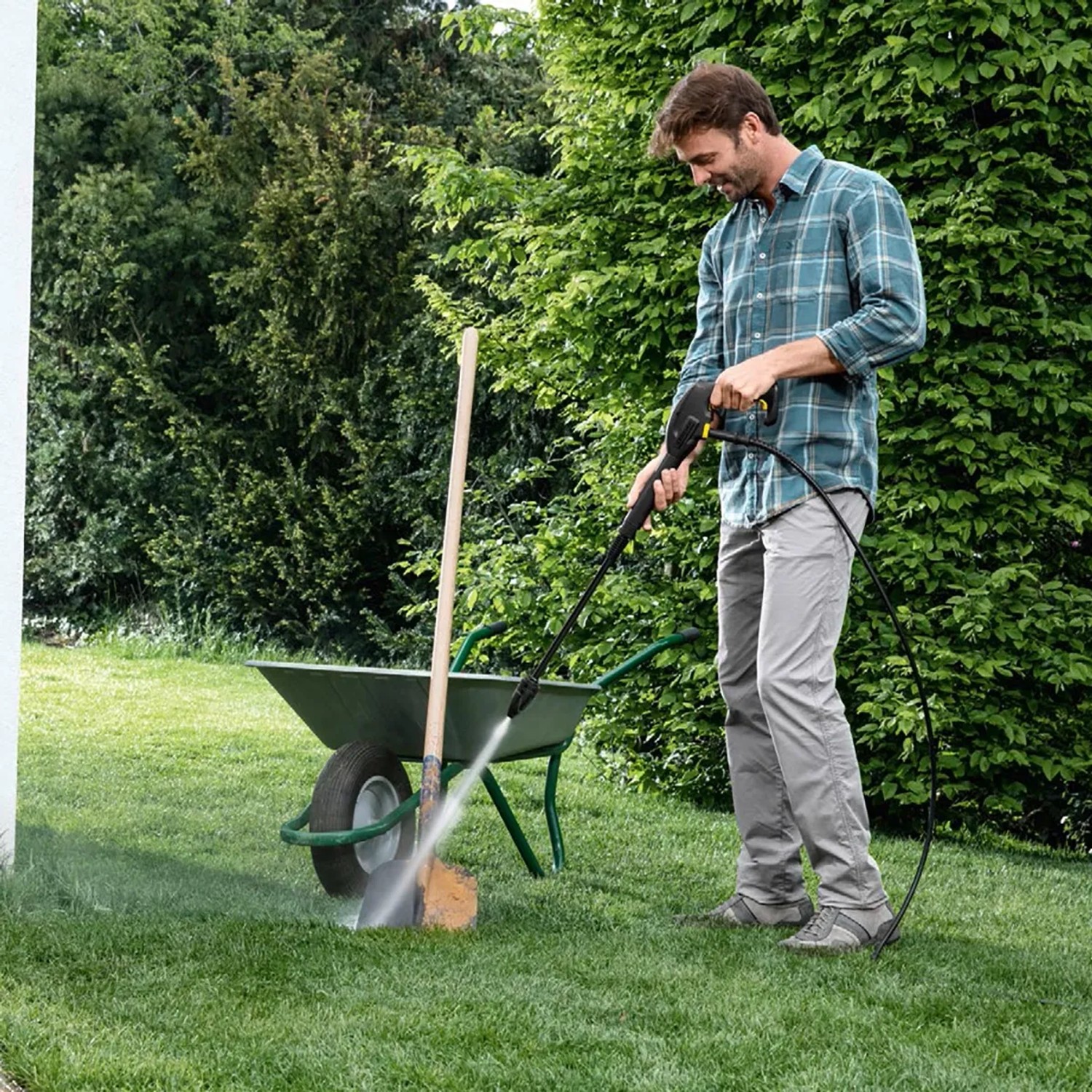 Kärcher K2 Universal Edition Hochdruckreiniger im Einsatz zur Reinigung einer Schubkarre im Garten.