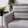 Dekoratives Andiamo Kissen Malena in Schwarz-Weiß mit geometrischem Muster auf grauem Sofa.