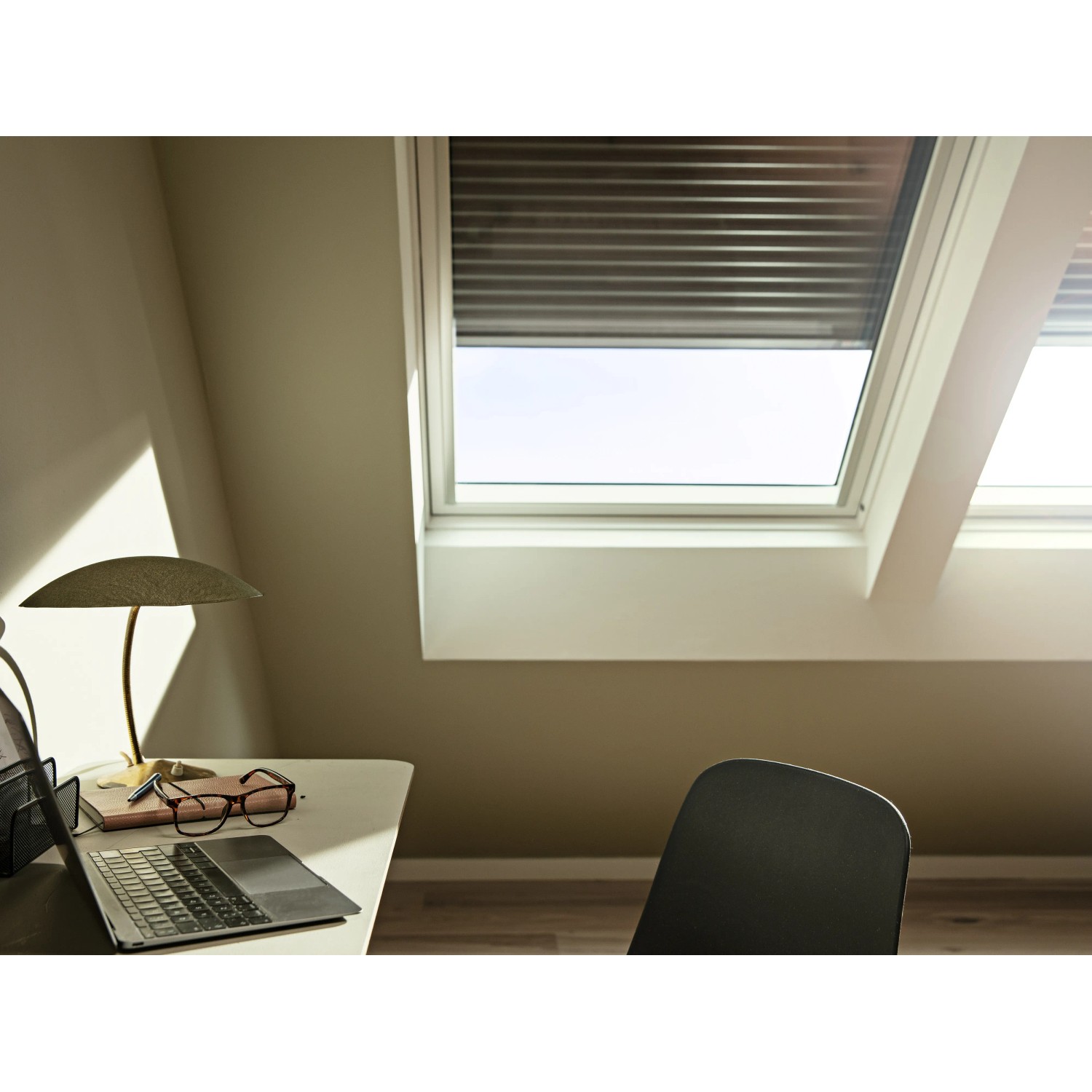 Velux Solar-Rollladen SSL CK02, dunkelgrau, teilweise geöffnet am Dachfenster im Dachgeschoss.