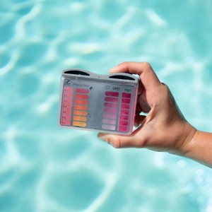 Bayrol Pooltester pH/Cl mit Farbskala zur Poolwasseranalyse in Hand über Wasser.