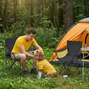 Mann und Hund sitzen auf Sunula Campingstühlen vor einem Zelt. Faltbarer Anglerstuhl mit Getränkehalter.