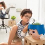 Kind betrachtet Lechuza Ojo Pflanzgefäß (Ocean Blue) mit Lupe. Spielerische Pflanzenpflege im Kinderzimmer.