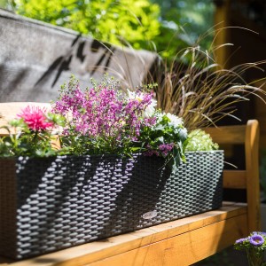 Lechuza Balconera Cottage 80 Blumenkasten in Granit mit bunten Blumen auf einer Holzbank.
