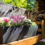 Lechuza Balconera Cottage 80 Blumenkasten in Granit mit bunten Blumen auf einer Holzbank.