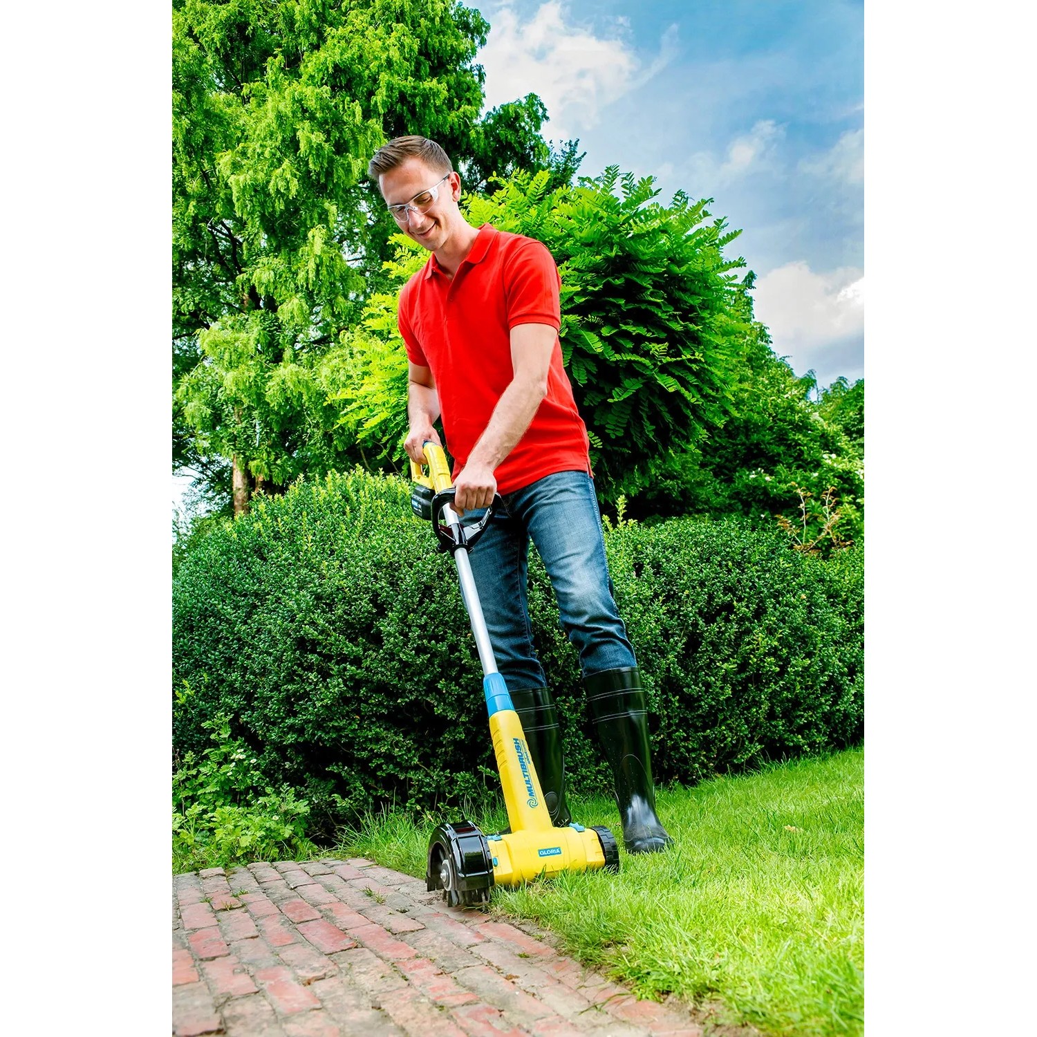 Mann nutzt Gloria Kantenschneider Cut&Brush 2-in-1 zur Rasenkantenpflege im Garten.
