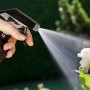 Hand sprüht mit brauner 500 ml Glas Sprühflasche (4er Set) Wasser auf eine weiße Rose. Verstellbarer Sprühkopf für Garten & Haushalt.