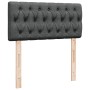 Dunkelgraues Boxspringbett Kopfteil mit Knopfheftung und Holzfüßen.
