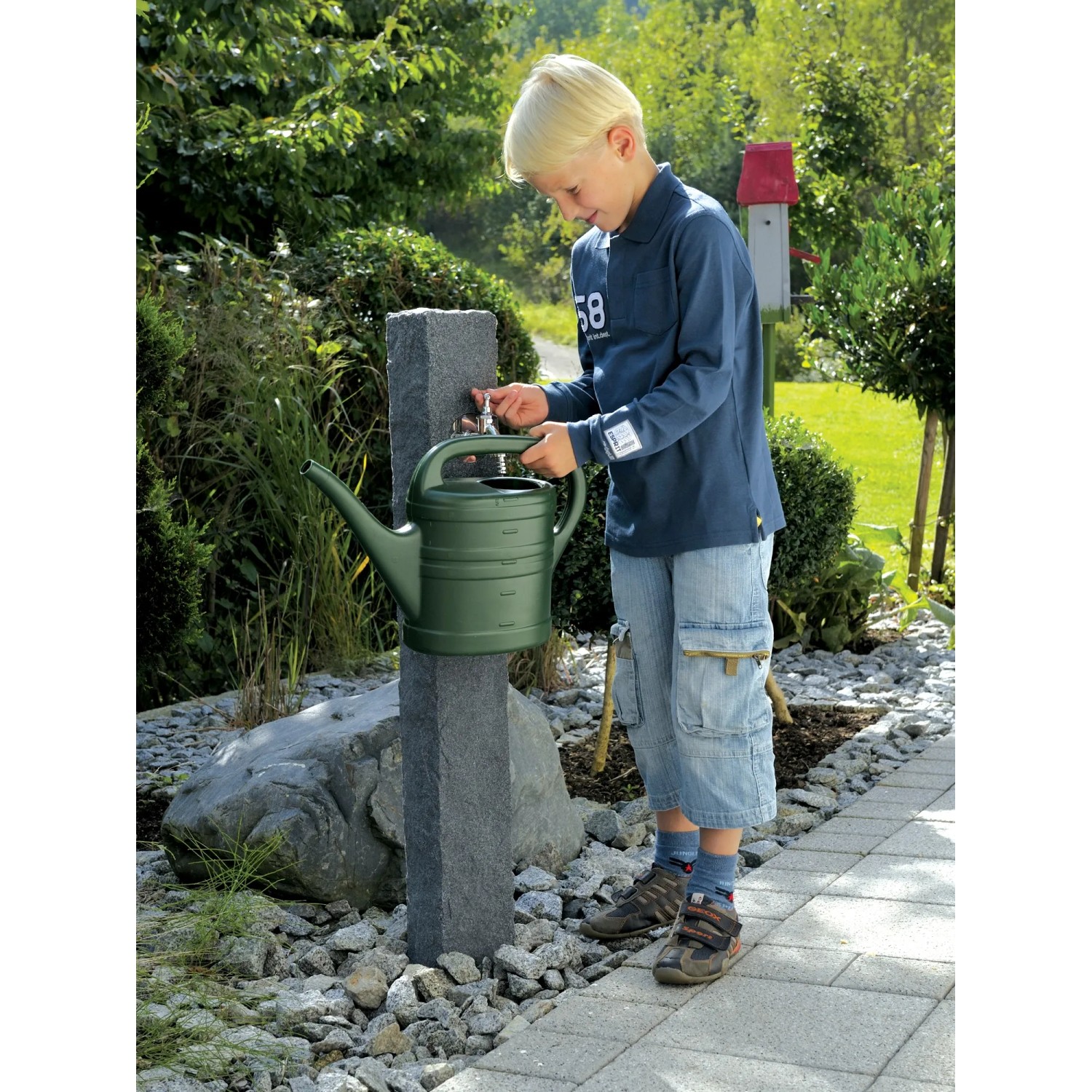 Arves Wasserzapfstelle Natura Black Granit mit Kind und Gießkanne im Garten.