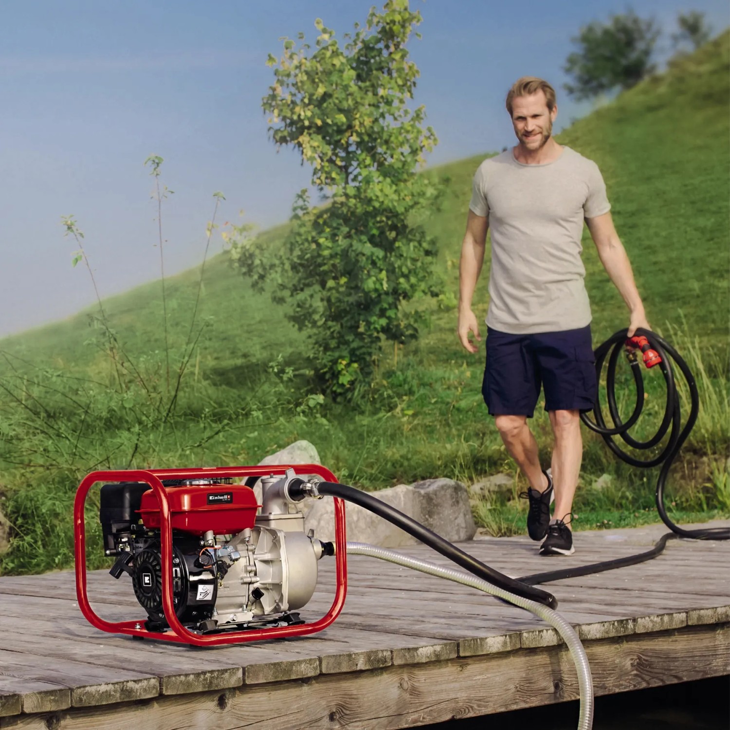 Einhell Benzin-Wasserpumpe GE-PW 46 im Einsatz: Rote Pumpe mit Mann auf Holzsteg am See.