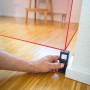 LUX-TOOLS Laserentfernungsmesser im Einsatz mit rotem Laserstrahl zur Messung eines Raumes.
