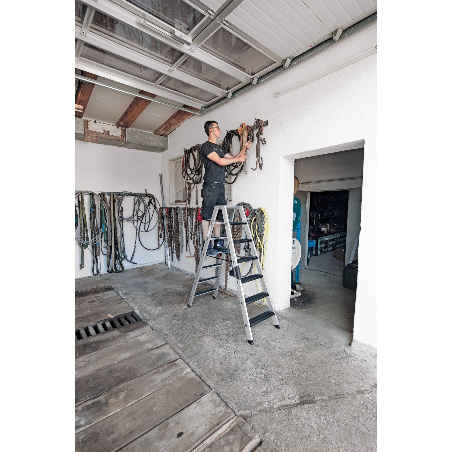 PROREGAL Stufen-Stehleiter, beidseitig begehbar, 2x7 Stufen, mit Mann auf der Leiter.