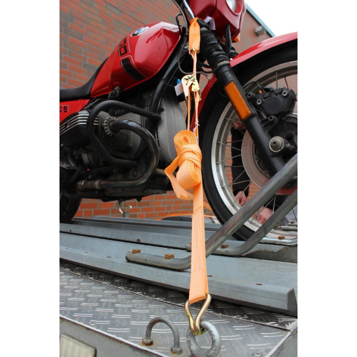 Motorrad auf Anhänger verzurrt mit TRUTZHOLM Gurtschlaufen und Spanngurten, orange.