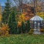 Sechseckiges Palram Canopia Oasis Gewächshaus im Garten mit Herbstlaub.