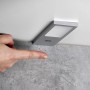 Flache, silbergraue SOTECH GIULIA II LED Unterbauleuchte mit Sensor. Eine Hand bedient die dimmbare Leuchte berührungslos.