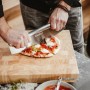 Enders Pizzaschneider aus Edelstahl schneidet Pizza auf Holzbrett. Grillutensil für perfekte Pizzastücke.