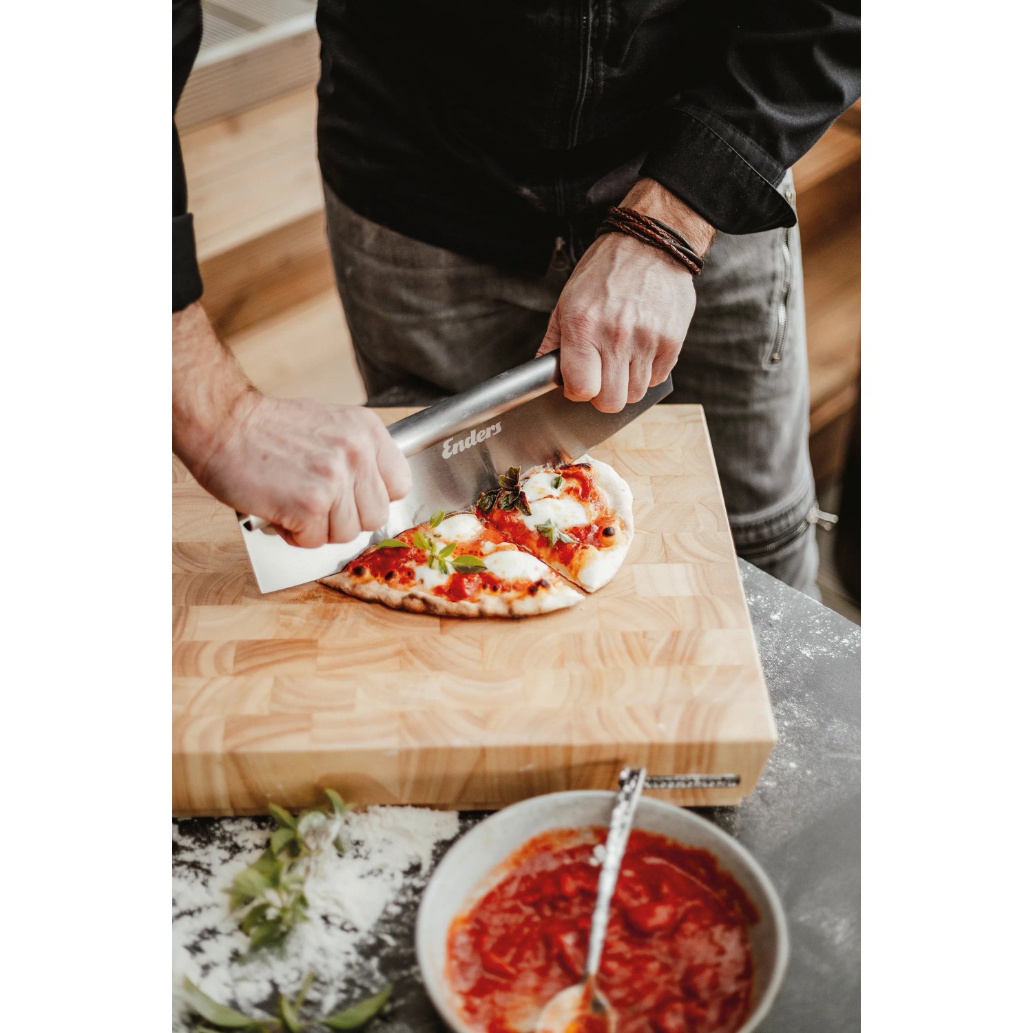 Enders Pizzaschneider aus Edelstahl schneidet Pizza auf Holzbrett. Grillutensil für perfekte Pizzastücke.