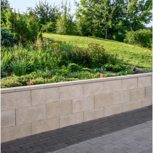 Graue Schalungsstein-Randstein-Mauer (50x25x24,5 cm) im Garten.