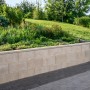 Graue Schalungsstein-Randstein-Mauer (50x25x24,5 cm) im Garten.