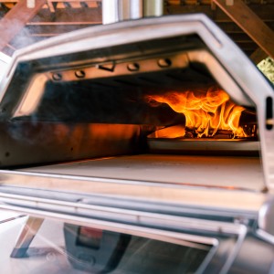Ooni Karu 16 Ofen mit brennendem Ooni Premium Eichenholz für authentisches Grillerlebnis.