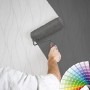 Überstreichbare Vliestapete mit geschwungenen Linien wird grau gestrichen.