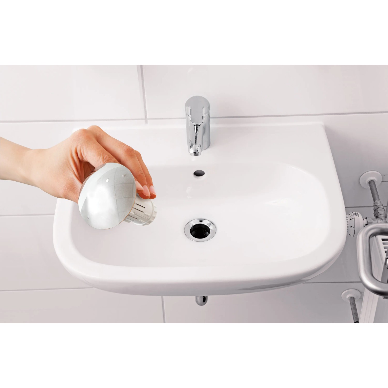 Abfluss-Fee Waschbeckenstöpsel Weiß-Chrom über einem weißen Waschbecken.