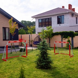 Zwei rote Relaxdays Fußballtore aus Eisen mit Netz im Garten. Ideal für Sport & Training von Kindern und Erwachsenen.
