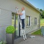 Mann auf Hailo Alu-Teleskopleiter FlexLine 260 (9-stufig) vor Hauswand. Leiter bis 150 kg belastbar.