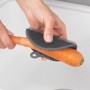Wenko Silikon Spülschwamm 2er-Set in Aktion: Eine Hand reinigt eine Karotte mit dem grauen Küchenhelfer.